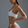 Oh Polly Ropa de baño: Top de bikini bandeau con un solo hombro y adornos, edición HOTFIX, en blanco