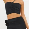 Partes de arriba asimétricas de jersey elástico con detalle de rosa de Tesia en negro