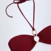 Top de bikini con cuello halter fruncido y detalles metálicos de Savai en color cereza oscuro