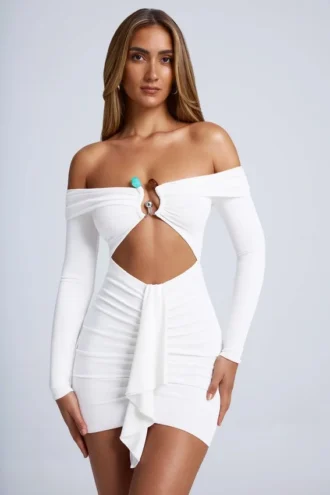 Vestido corto blanco con hombros descubiertos y aberturas, con detalles metálicos, en color azafrán