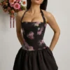 Vestido corto con cuello halter, cordones y bajo abullonado Nanala en estampado floral negro