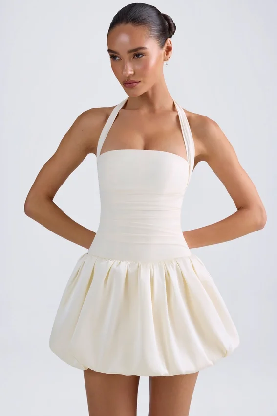 Vestido micro corto con corsé, cuello halter y bajo abullonado con cordones Ludmila en color marfil