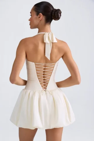 Vestido micro corto con corsé, cuello halter y bajo abullonado con cordones Ludmila en color marfil