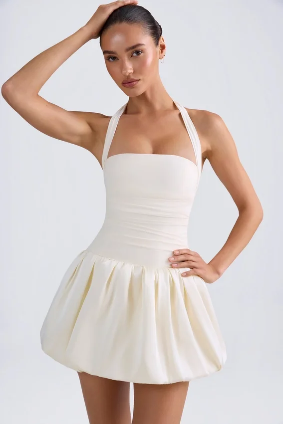 Vestido micro corto con corsé, cuello halter y bajo abullonado con cordones Ludmila en color marfil