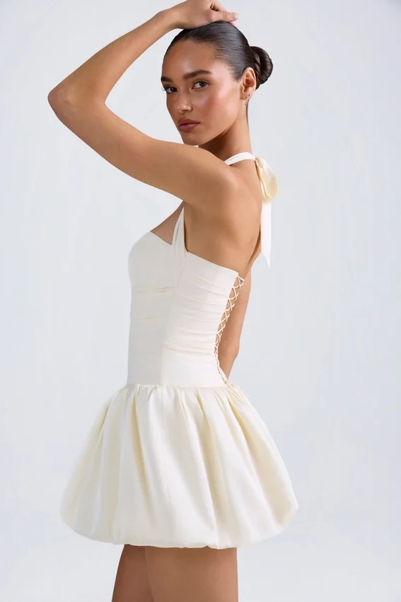 Vestido micro corto con corsé, cuello halter y bajo abullonado con cordones Ludmila en color marfil